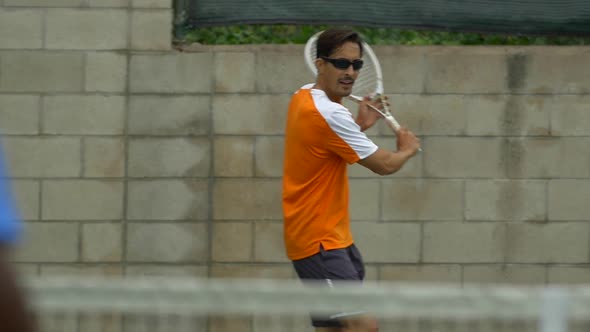 Two men playing outdoor tennis together. alt