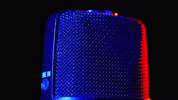 Condenser Microphone Rotates with Blue and Red Backlight. Professional Audio Recorder Close-up alt