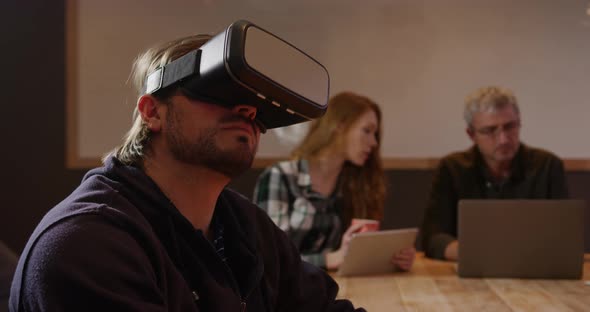 Man wearing VR headset with colleagues working in creative office alt