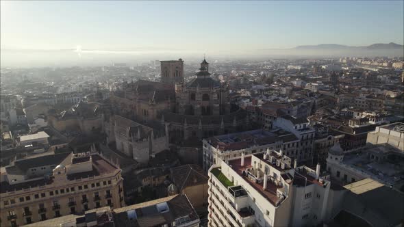 Cathedral of Incarnation with sun shining in sky and foggy landscape in background, Granada in Spain