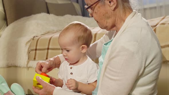 Baby Sitting on Knees of Grandmother and Playing