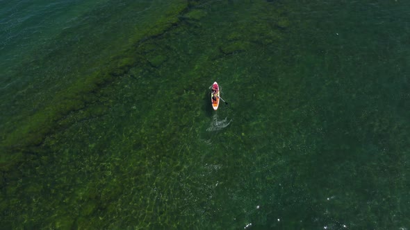 People on a paddle board or SUP on the sea, crossing the breakwater, aerial view