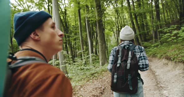 Backpacked Tourists Walking in Forest Backview