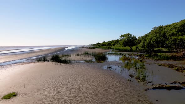 Low level aerial drone forward flying capturing the unique riverbanks sand texture, sandy tidal flat alt