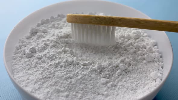 The dental powder applies to a wooden toothbrush. Gently blue background