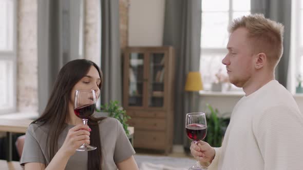 Young Woman and Man with Glasses of Red Wine Dancing alt