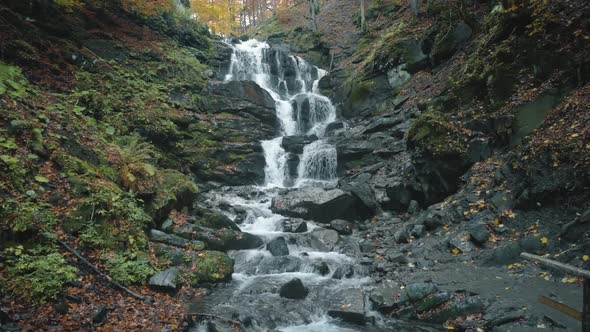 Water Falls From Large Rocks Surrounded By Fallen Leaves