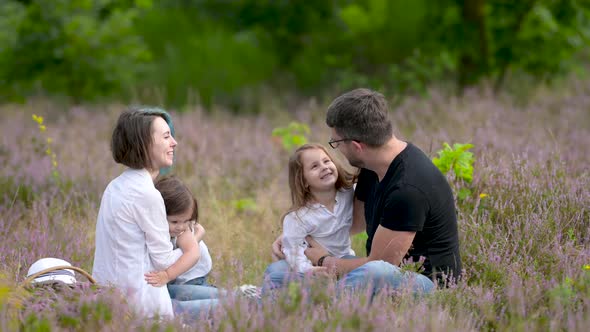 Happy smiling family resting on a green meadow.