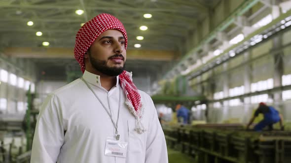 Joyful Arabian businessman staying at factory