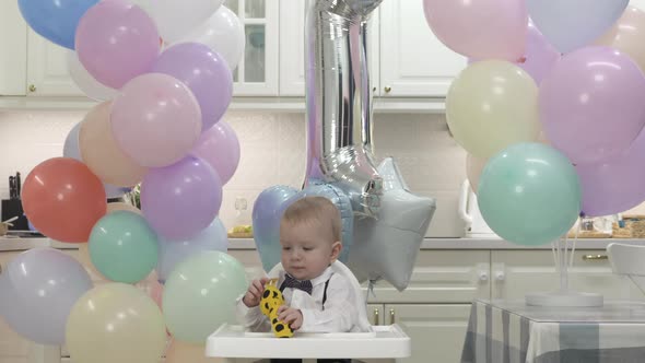 Happy Little Boy Holding Gift Toy at Birthday Party in Slow Motion One Year Old Kid Against Colorful alt