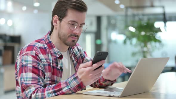 Professional Male Designer Using Smartphone and Laptop alt