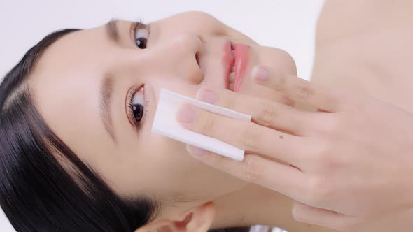 Slow Motion Beauty Portrait Of Young Attractive Asian Woman Cleaning Face With Cotton Pad Gently. alt