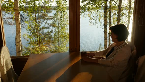 Attractive Woman Sitting by Window Enjoying Beautiful Lake 