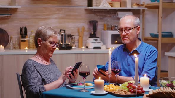 Old Couple Using Phones in the Kitchen alt