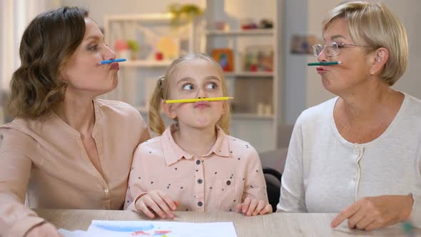 Funny Multigeneration Females Holding Color Pencils Between Nose and Lips, Game alt