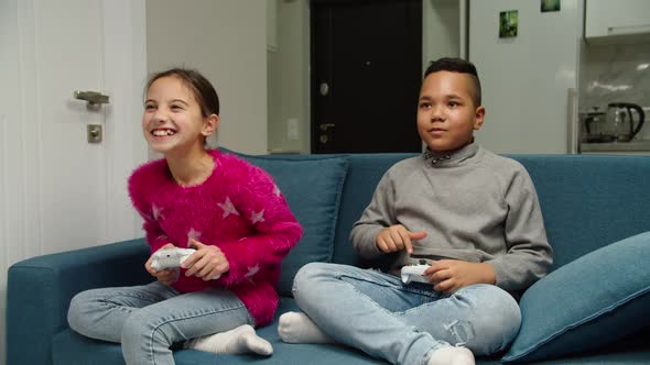 Multiethnic Preteen Friends Competing By Playing Video Game Indoors alt