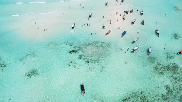 Motorboats cruising around shallow tropical sandbank with people. Mnemba Island. alt