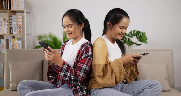 Twin girls playing on the smartphone at living room. alt