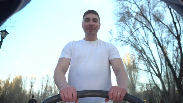 A Young Father Walks with a Baby in a Stroller in the Park alt