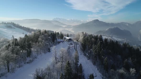 Aerial view of beautiful winter mountain snowy scenery. Cable car with skiers is riding