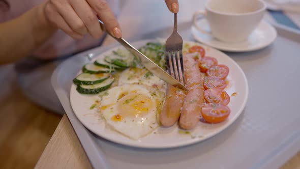High Angle View of Female Hands Cutting Sausage on Plate in Restaurant or Cafe alt