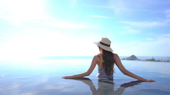 Young asian woman enjoy around outdoor swimming pool for leisure alt