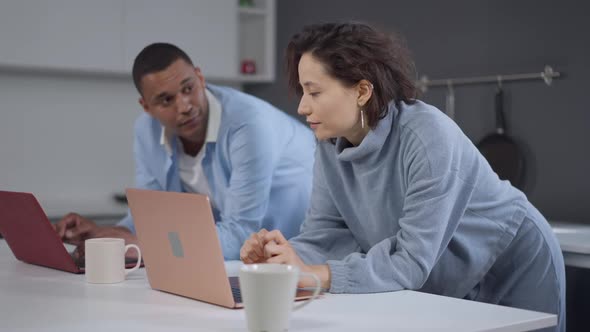 Side Angle View of Concentrated Caucasian Woman and African American Man Typing on Laptop Keyboard alt