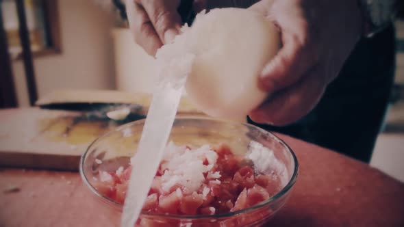 hands close up cutting a onion in small pieces to make salad alt