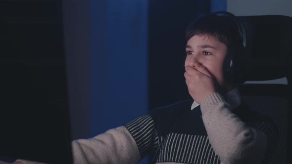 Scared Boy in Headphones Shocked By Terrible Scene While Watching Horror Video on Computer alt