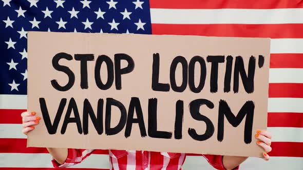 Protester Holds a Banner with a Slogan - Stop Vandalism and Looting - Against Background of the USA alt