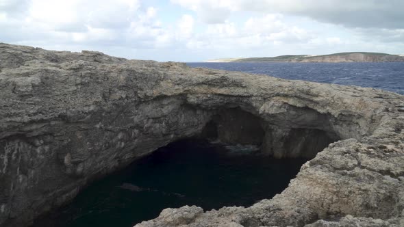 Panoramic View of Coral Lagoon Cave in Malta Filled with Depp Water on a Windy Day alt