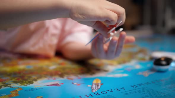 Closeup of Little Boy Playing with Small Toy Airplane on Big World Map alt