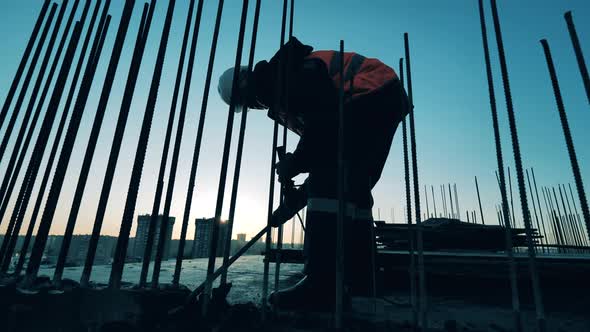 Man in Uniform Drills Floor in Unfinished Building. Construction Site, Construction Industry alt