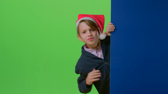 Child Boy Holding Hands on the Board Appears To Her in a Christmas Hat on a Green Screen alt