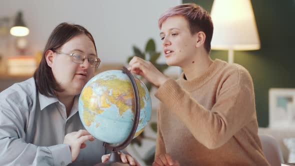 Man with Down Syndrome Learning World Map on Globe with Teacher alt