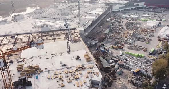 Drone Flying Over the Construction Site of a Shopping Center with Construction Equipment and Workers