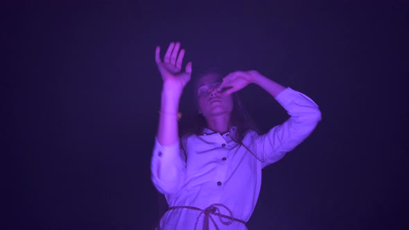 Slow ecstatic dancing woman in dark night club with purple light meditative music rhythm expression