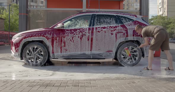 Man Washing Her Car in a Self Service Car Wash Station alt