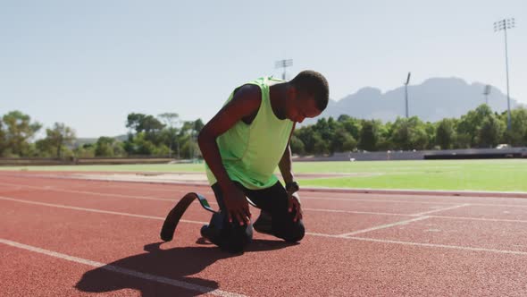 Disabled mixed race man with prosthetic legs sitting on race track and cheering for himself alt