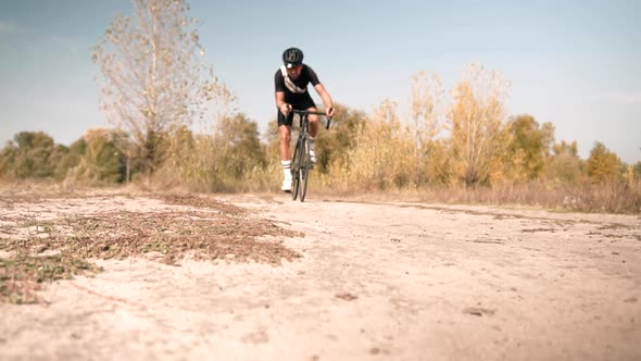Cyclist Riding On Gravel Bike In Slow Motion. Cyclist Athlete Workout Riding On Gravel Bicycle. alt