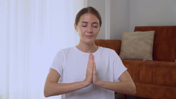 A Woman Meditates Palms in Namaste in Front of Her Chest