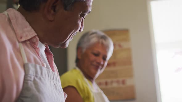 Happy senior mixed race couple wearing aprons preparing food iand smiling alt