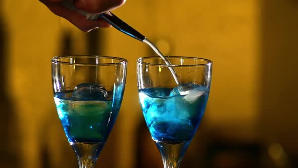 Barman Making Cocktails at the Night Club, Using Two Glasses with Ice Adding Cloudy White Liquid alt