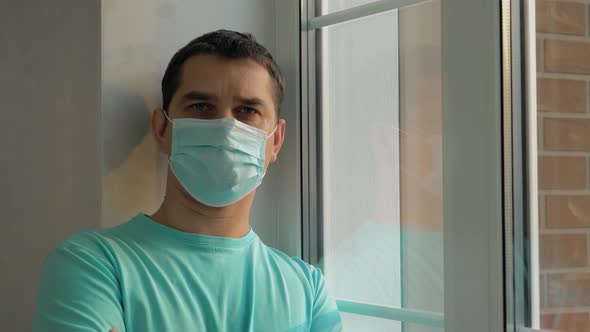 Man in a Blue Medical Mask Looks at the Camera