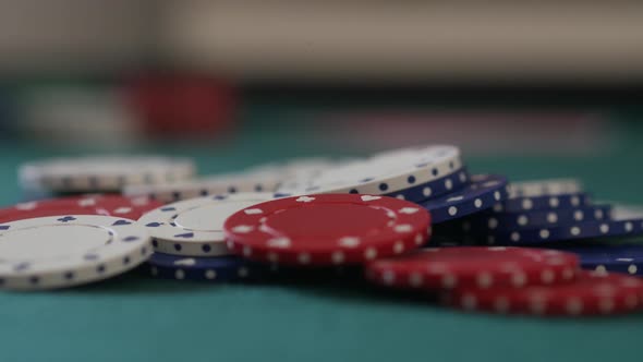 Close-up of a pile of poker chips on a table as more are added to the pile as betting takes place alt
