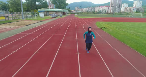 Cinematic Shot of Young Arab Sportswoman with Athletic Body in Hijab Running with Effort and alt