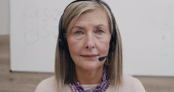 Portrait of Mature Woman in Wireless Headset with Microphone Looking To Camera alt
