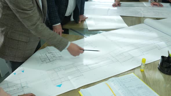 three businessmen in business office look at architect drawing alt