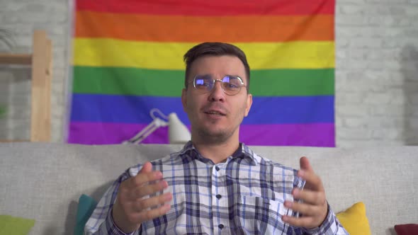Man Blogger Middleaged in the Shirt on the Background of the Flag of the LGBT Records Video Close Up alt