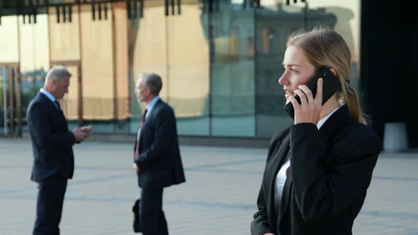 Businesswoman Making Phone Call, Business Phone Sales, Colleagues in the Background